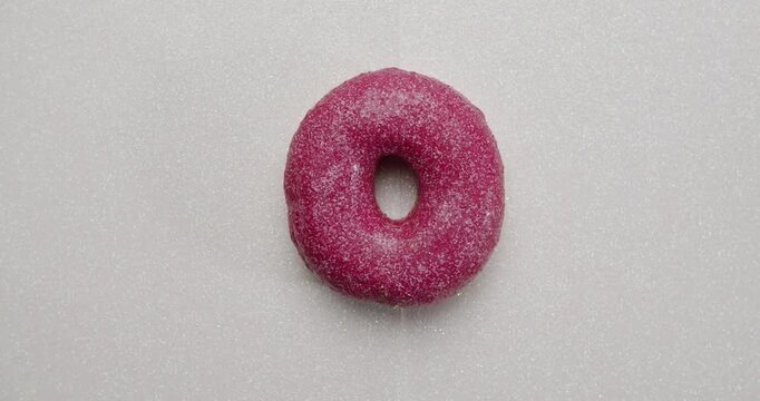 Variety of fresh, sweet, and glazed donuts with different colorful toppings and sprinkles appearing one by one in a continuous vertical sequence isolated on a clean white background. stop motion