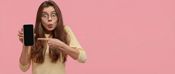 Smartphone Presentation: A surprised individual showcases a smartphone with a blank screen, highlighting the user-friendly interface against a plain backdrop.