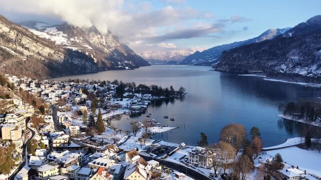 Walensee, Switzerland winter aerial of snowy lakeside village, alpine mountains, calm blue water, nature landscape in cold season.