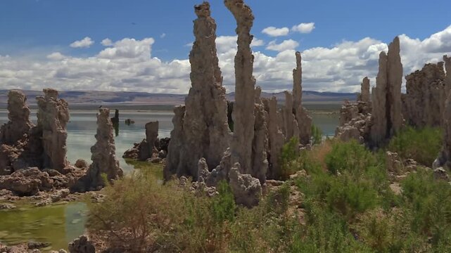 Towering tufa formations with rugged textures and scattered desert brush near Mono Lake, California. Pan left shot