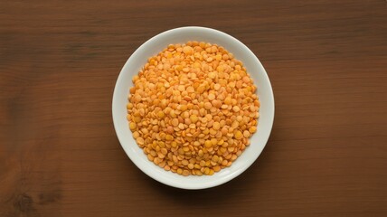Vibrant orange lentils in a white bowl on a wooden table