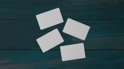 Four blank white cards on dark wooden background
