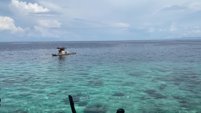 The atmosphere of the beach is very calm with the shoreline stretching horizontally. The water is a clear green, like emerald.