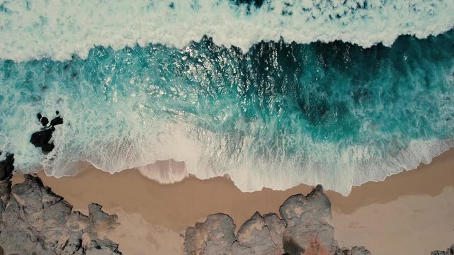 Cinematic aerial of gentle waves moving across a beach in Cabo San Lucas, Mexico