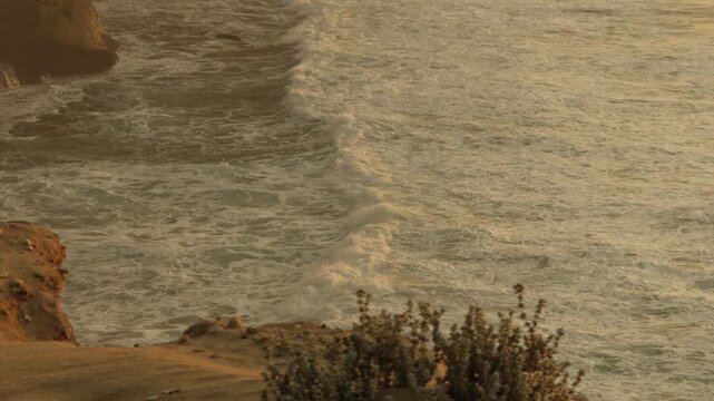 Desert dunes rising above ocean cliffs in Morocco at sunset, cinematic coastal travel landscape from a ground level