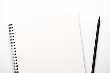 White notebook with black pencil lies on white background.