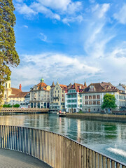 Fototapeta premium Zurich, Switzerland, May 01, 2025. Picturesque riverside walkway with wooden railings overlooking the historic colorful buildings of old town Zurich. High quality photograph.