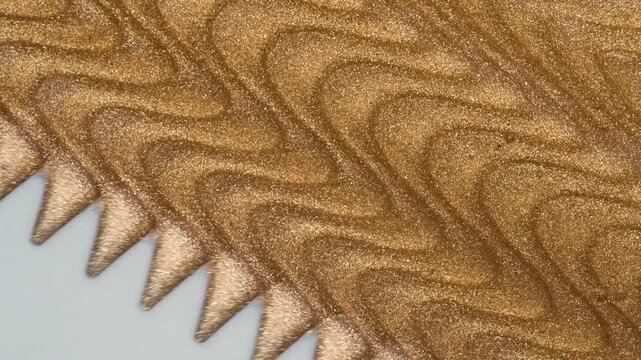 Liquid gold background. Golden waves of liquid gold polish or lip gloss texture, mixing with plastic spatula