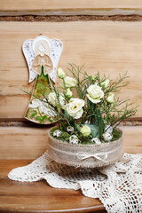 Florist at work: woman shows how to make simple Easter centerpiece with eustoma flowers, green twigs and moss in the glass stand. Step by step, tutorial.