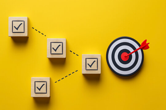 Four Wooden Blocks with Three Checks and Dotted Arrows to Target &mdash; Strategic Pathway, Non-Linear Progress, and Adaptive Goal Achievement Concept
