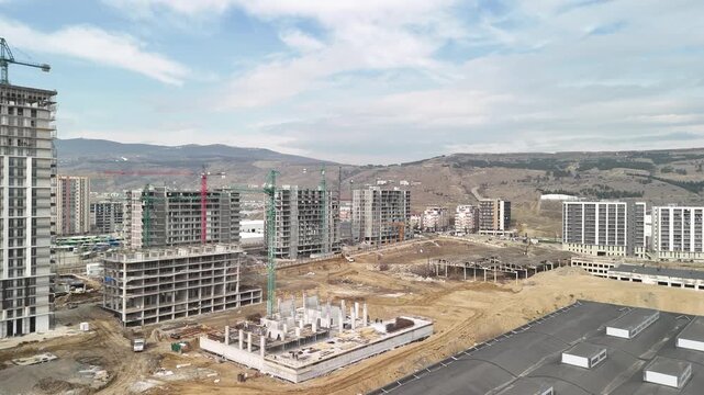 Expansive urban construction site showcasing the initial phase of a new residential district with several high rise apartment buildings under development and tower cranes working