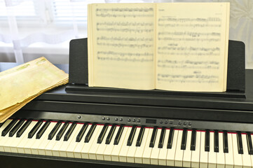 Music book standing on electronic piano, symbolizing creativity and practice