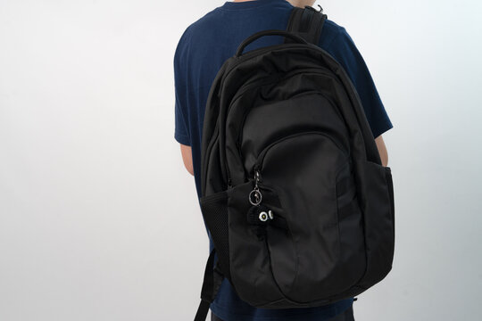 Side view of a young Asian man wearing a black backpack decorated with a small black handmade crochet cat  for mockup or branding