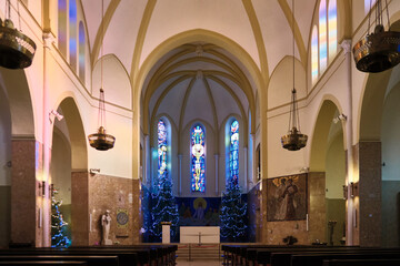 Obraz premium Interior of historic church, looking toward the altar framed by high vaulted arches and illuminated stained glass windows. Franciscan Friary and the Church of Saint Anthony of Padua, Sarajevo