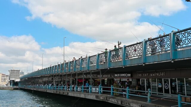 Istanbul,turkey,august 13, 2025. Numerous fishermen lining the upper deck of the galata bridge, casting their rods into the golden horn on a sunny day