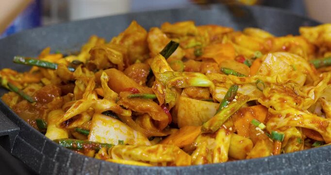 The Korean-style spicy stir-fried spring chicken, tossed on a heated iron plate, has an enticing reddish-brown color, creating a delicious atmosphere perfect for sharing during a meal.