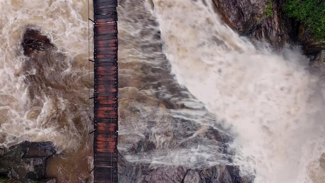 The image showcases Bambarakiri Ella Falls, a picturesque 3-meter waterfall near Rattota in Matale, Sri Lanka, surrounded by lush evergreen forest and featuring a charming suspension bridge