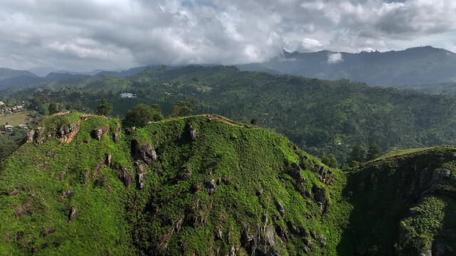 Hikers walk on the mountain trail lying on the edge of the cliff with stunning valley views. The place named Little Adam's Peak in Ella, Sri Lanka