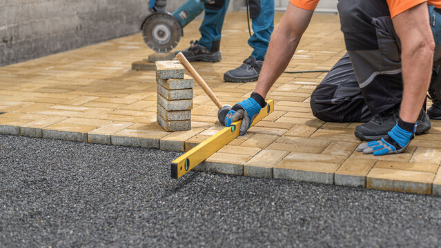 Laying interlocking paving. Leveling the block using a spirit level.