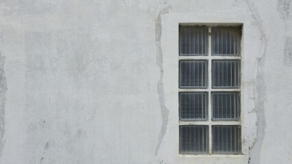 Background of an old stained gray stucco wall, showing rough texture and dirt marks, with industrial-style glass block windows. Ideal for grungy design projects.