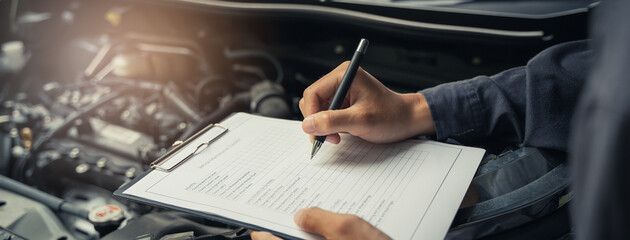 Naklejka premium Auto check up and car service shop concept. Mechanic writing job checklist to clipboard to estimate repair quotation to client at workshop garage.