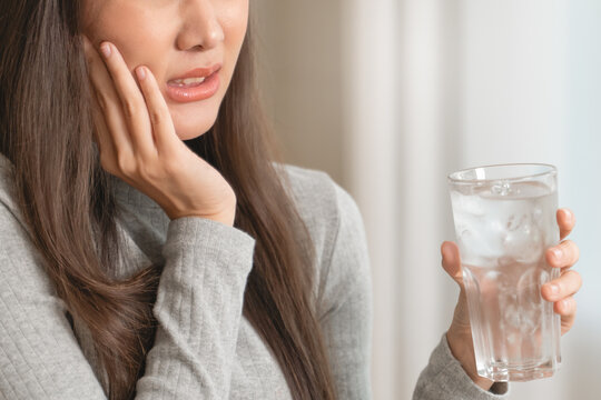 Face expression suffering from sensitive teeth, Asian young woman touching cheek