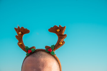 Man in reindeer antlers on a beach. Non-traditional holiday concept. Copy space. © Evgeniya