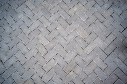 Top view of grey rectangular paving blocks in a classic herringbone pattern. Perfect for architectural and urban landscape backgrounds