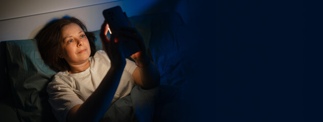 Lonely woman in bed at night using smartphone and suffering from insomnia, female holding mobile phone during sleepless night in dark bedroom © Andrii Lysenko