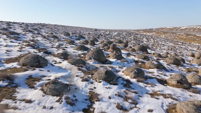 4K drone footage of a vast field of round stone concretions of various sizes with a white off-road vehicle in the distance. Scenic winter landscape of the Torish Valley of Balls in Mangystau