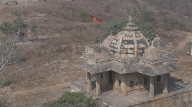 ancient stone "parvati temple" located at the base of the "chaurasan temple", with a bright devotional flag fluttering against the kaimur hill backdrop