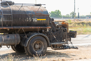 Fototapeta premium Industrial oil tanker refueling action construction site urban area vehicle daylight ground level