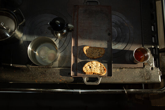 Rustic breakfast prep: toasted bread and pots on a vintage wood-burning stove.