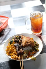 Nasi Rames - Chicken rice with noodles and vegetables on the table ready to eat