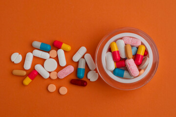 Various colorful prescription antibiotic capsules on jar bottle plastic onto a orange background. Various colorful prescription capsule pills. Ideal for healthcare, pharmaceutical treatments