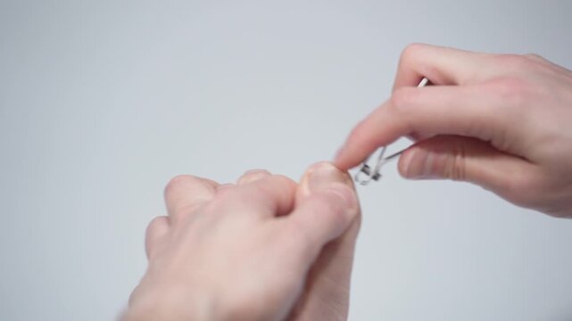 Man is cutting her nails on toes using nippers by herself, closeup view. Hygiene and care for feet.