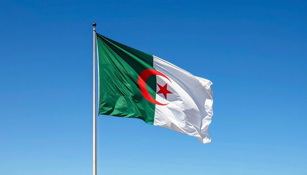 The Algerian flag proudly waving in the wind, set against a stunning backdrop of a clear blue sky and majestic mountains. A powerful symbol of national pride and identity.