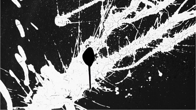 Close-up of a black and white paint splatter design with a single drop falling against a dark background.