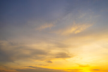 Obraz premium Beautiful sunset sky with orange clouds and blue gradient background,Vibrant sunset sky featuring soft wispy clouds illuminated by golden light, transitioning from deep blue to bright orange.