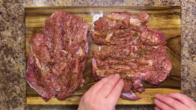 Preparing the turkey thigh for the roulade. The process: hand-roll the prepared piece of meat with spices on a wooden board.