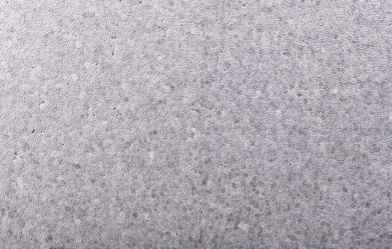 Close-up texture of gray foam plastic with granules.