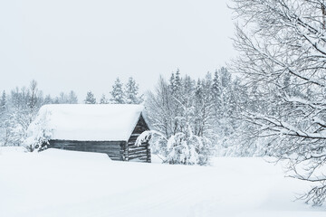 Old wooden building stands in snow covered forest in Sweden during winter season