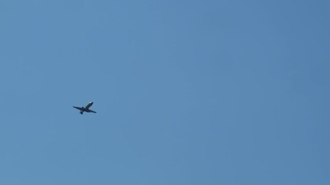 Static shot of an airplane flying in clear sky, from long distance in slow motion at 50fps