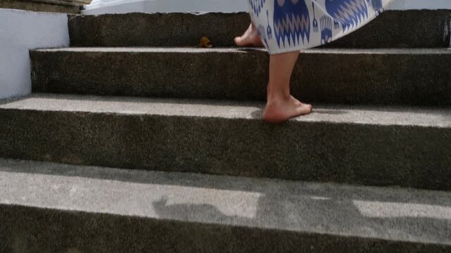 A woman walks barefoot on the steps of the Sima Malaka Temple located on Lake Beira in Colombo, Sri Lanka. Respecting the religious traditions and way of life of the local population, the tourist show