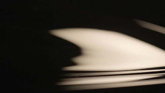 Abstract close-up of blurred white and black curved lines with a shallow depth of field on a dark background.