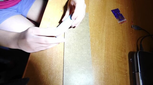 The video shows hands carefully peeling bubble wrap from a package of candle-making supplies on a wooden table. The process is done slowly to reveal the contents. The lighting is bright, making it eas