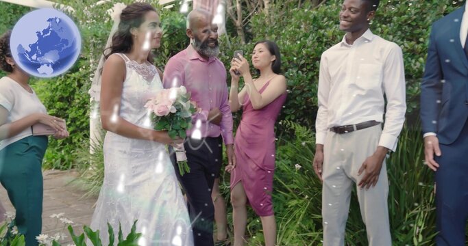 Walking bride in white lace gown and veil holding pale pink rose bouquet at garden pathway