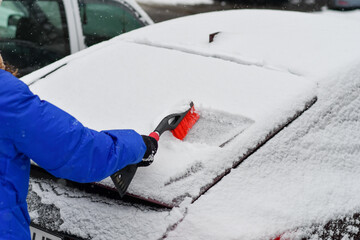Removing snow from car windshield with ice scraper on cold winter morning. Selective focus. 