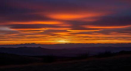 A breathtaking sunset over a mountain range with vibrant orange clouds