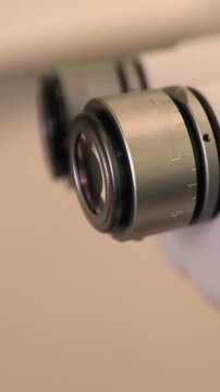Close up video footage of a medical doctor eye positioned at the binocular eyepieces of a laboratory microscope. Scientific research process shown through precise focus adjustment and examination 